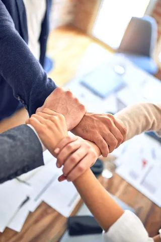 Four people grabbing each others wrists to make a square